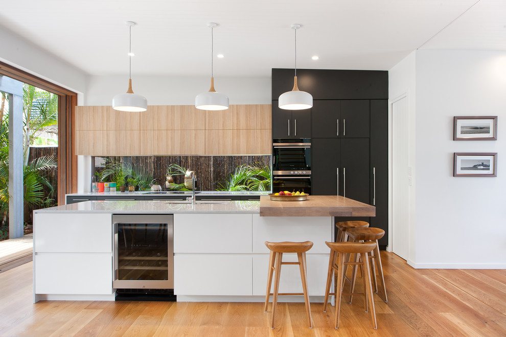 Contemporary kitchen in Brisbane with an undermount sink, flat-panel cabinets, black cabinets, medium hardwood floors, with island, quartz benchtops and window splashback.