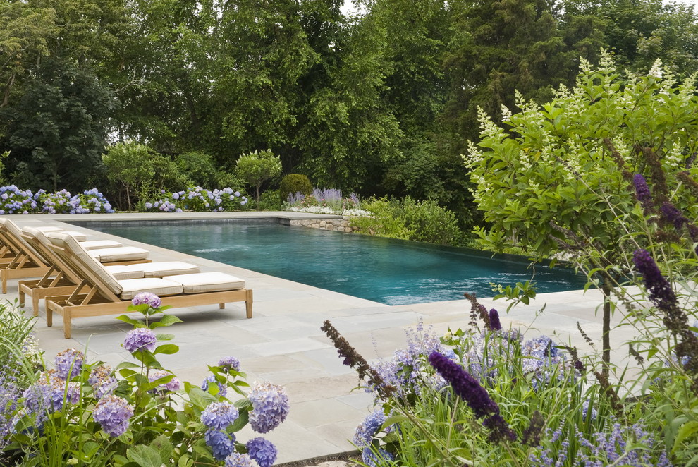Traditional backyard garden in Providence with natural stone pavers for summer.