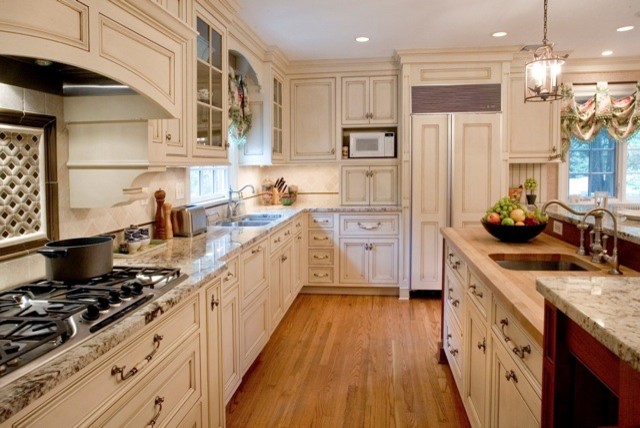 Example of a large transitional u-shaped medium tone wood floor eat-in kitchen design in New York with distressed cabinets, beige backsplash, white appliances and an island