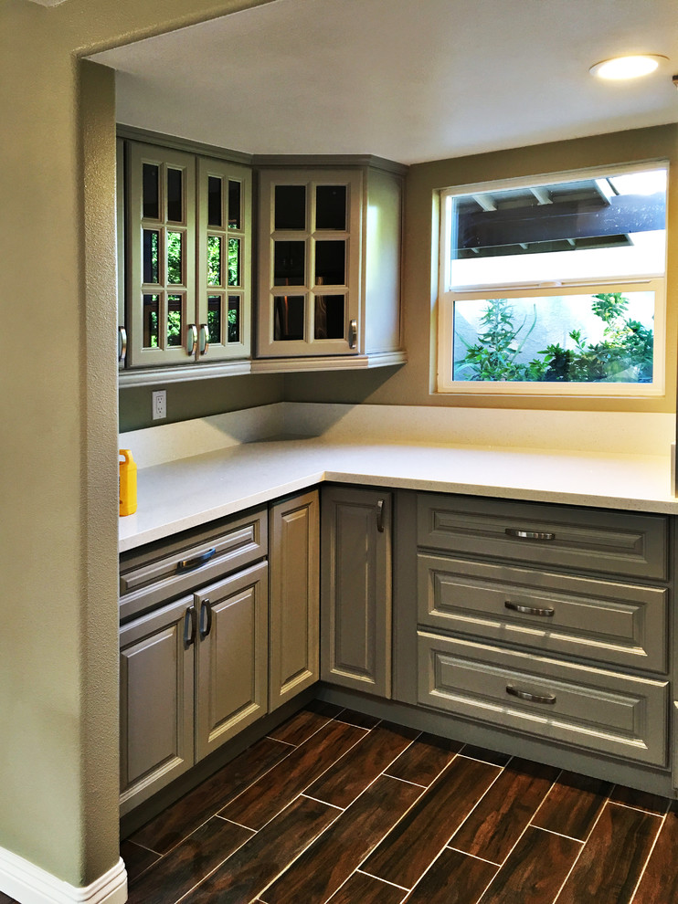Inspiration for a mid-sized transitional u-shaped medium tone wood floor eat-in kitchen remodel in Orange County with raised-panel cabinets, gray cabinets, quartz countertops, a peninsula, a double-bowl sink, brown backsplash, mosaic tile backsplash and stainless steel appliances