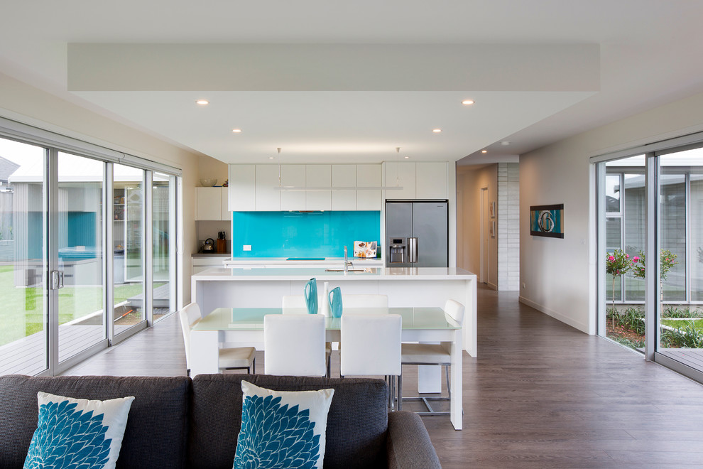 Inspiration for a contemporary galley open plan kitchen in Other with flat-panel cabinets, white cabinets, stainless steel appliances and glass sheet splashback.