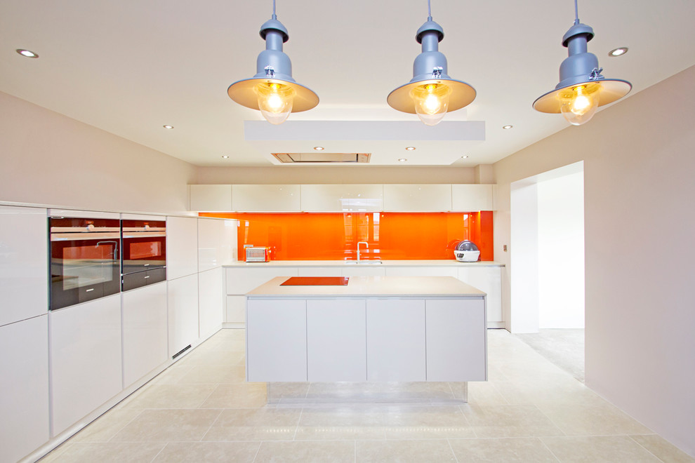 Immagine di una grande cucina minimal con lavello da incasso, ante beige, top in granito, paraspruzzi arancione, paraspruzzi con lastra di vetro, elettrodomestici in acciaio inossidabile e pavimento in pietra calcarea