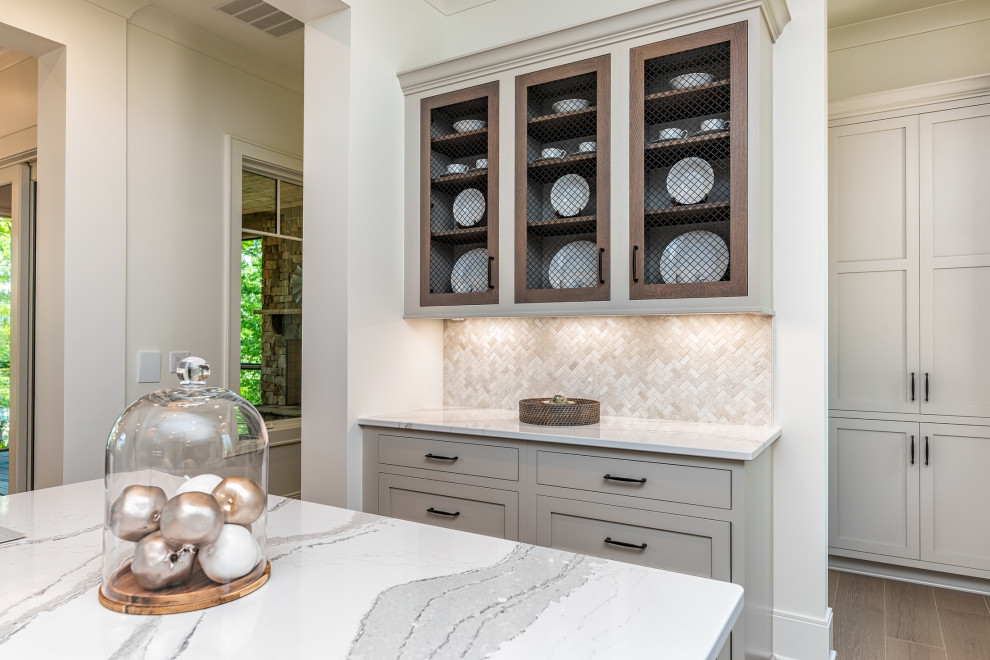 Example of a transitional u-shaped medium tone wood floor and brown floor kitchen design with an undermount sink, shaker cabinets, gray cabinets, quartz countertops, gray backsplash, mosaic tile backsplash, stainless steel appliances, an island and gray countertops