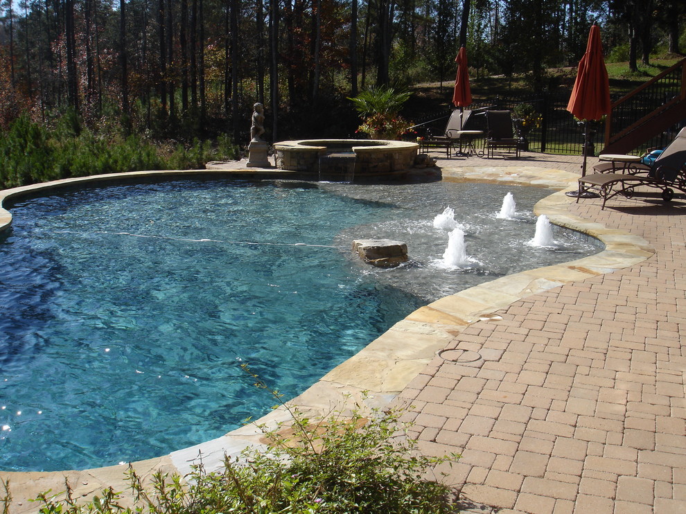 Large mediterranean backyard custom-shaped pool in Atlanta with a hot tub and brick pavers.