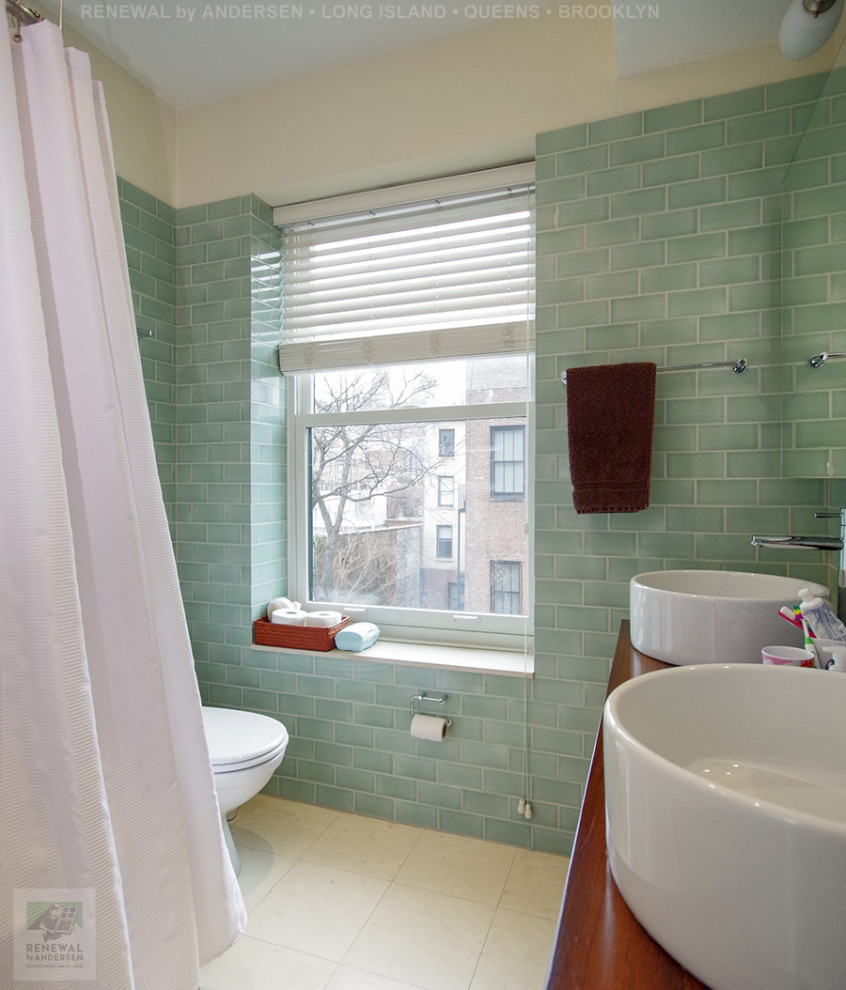 Photo of a medium sized bathroom in New York with medium wood cabinets, a freestanding bath, a shower/bath combination, a one-piece toilet, green tiles, metro tiles, green walls, ceramic flooring, a vessel sink, wooden worktops, beige floors, a shower curtain, double sinks and a freestanding vanity unit.
