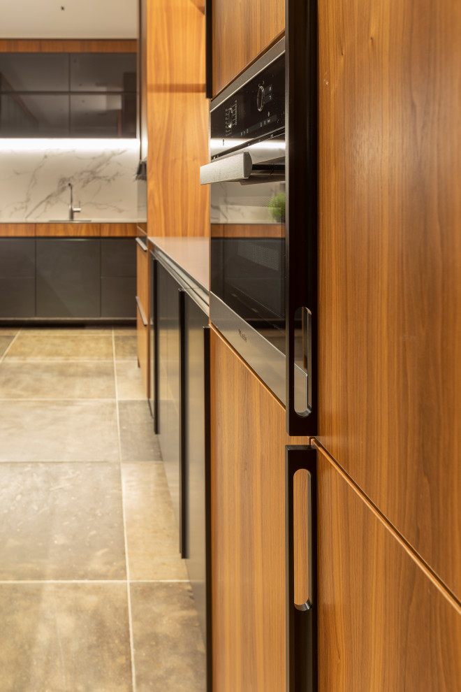 Design ideas for an expansive contemporary u-shaped kitchen pantry in Auckland with a submerged sink, flat-panel cabinets, black cabinets, composite countertops, black appliances, ceramic flooring, an island, brown floors, porcelain splashback and grey splashback.