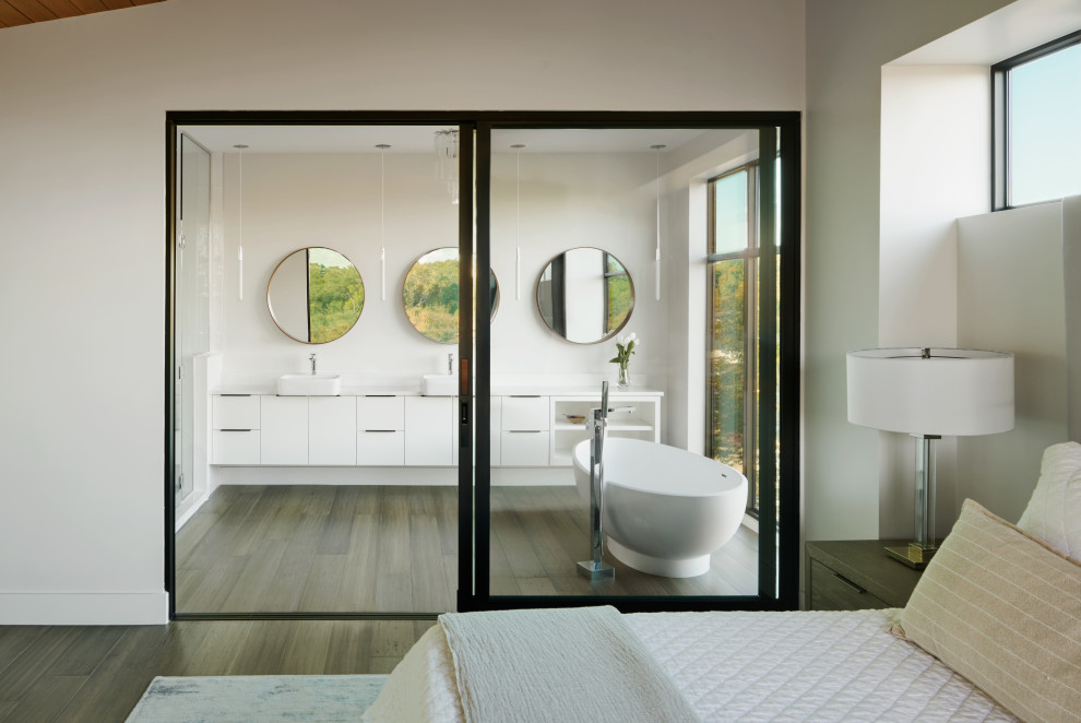 Mid-sized modern master bathroom in Austin with flat-panel cabinets, white cabinets, a freestanding tub, a wall-mount toilet, grey walls, bamboo floors, a vessel sink, engineered quartz benchtops, grey floor, a hinged shower door, white benchtops, an enclosed toilet, a double vanity and a floating vanity.