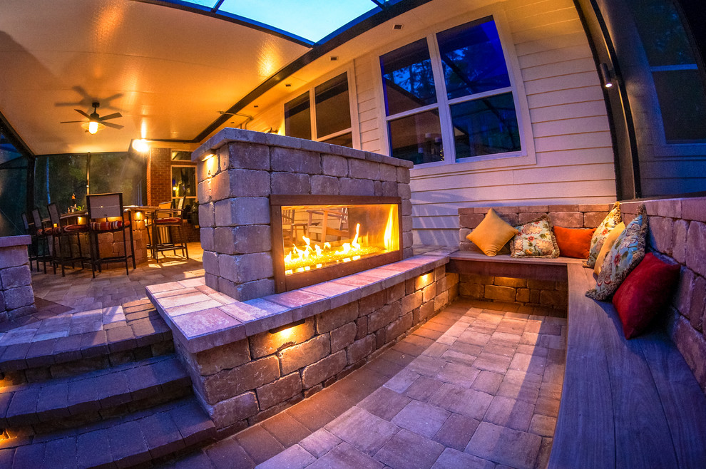 This is an example of a large contemporary backyard verandah in Jacksonville with a fire feature, natural stone pavers and a roof extension.