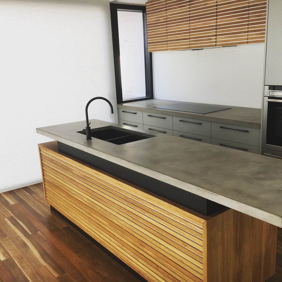 This is an example of a contemporary single-wall kitchen in Adelaide with flat-panel cabinets, grey cabinets, concrete benchtops, stainless steel appliances, with island, a double-bowl sink, white splashback and dark hardwood floors.