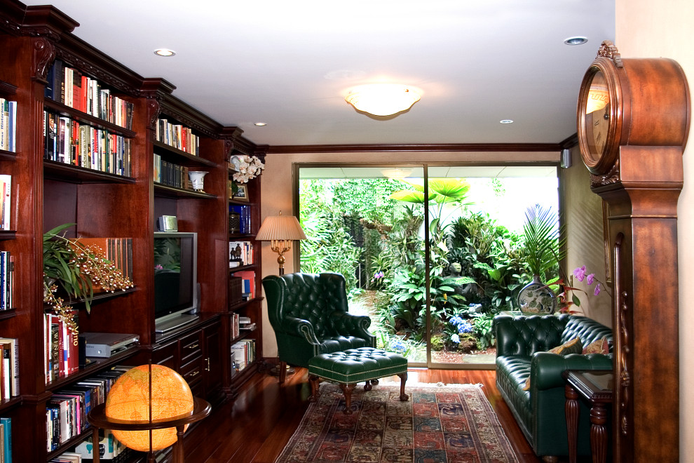 Geräumiges Klassisches Lesezimmer mit brauner Wandfarbe, dunklem Holzboden, Einbau-Schreibtisch, braunem Boden und Wandpaneelen in Sonstige