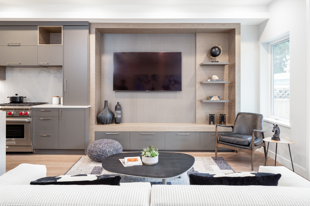 This is an example of a contemporary open concept living room in Vancouver with white walls, medium hardwood floors, a wall-mounted tv and brown floor.