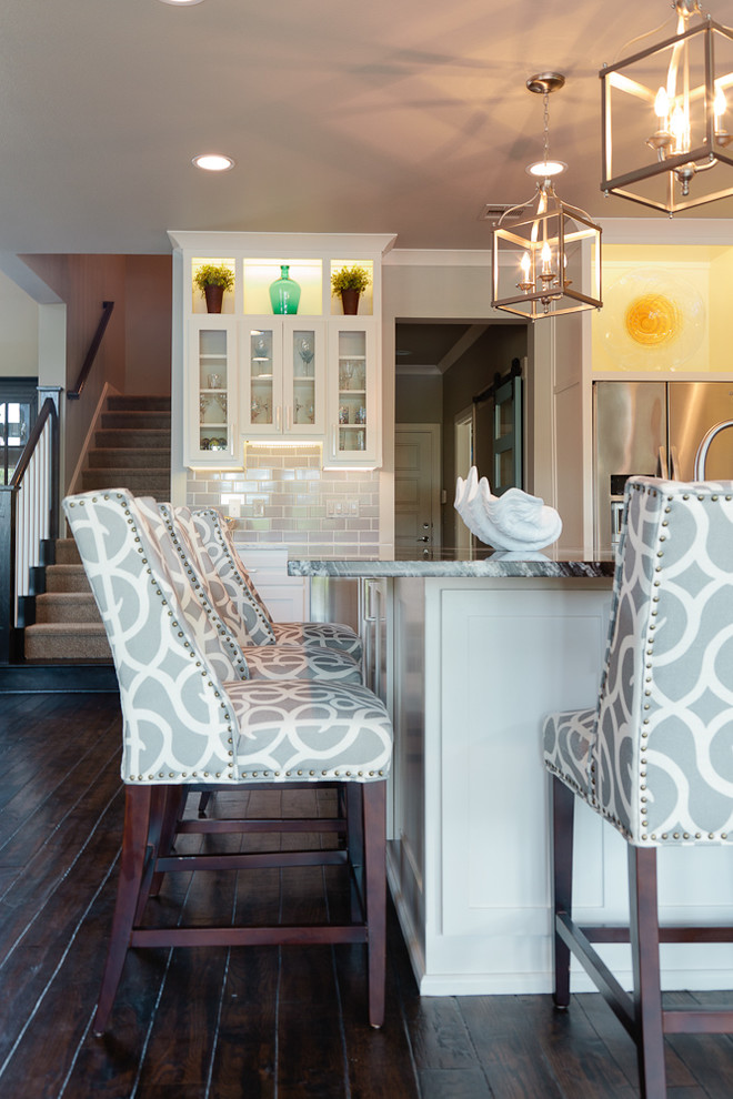 Example of a mid-sized beach style u-shaped dark wood floor eat-in kitchen design with an undermount sink, shaker cabinets, white cabinets, granite countertops, gray backsplash, glass tile backsplash, stainless steel appliances and an island