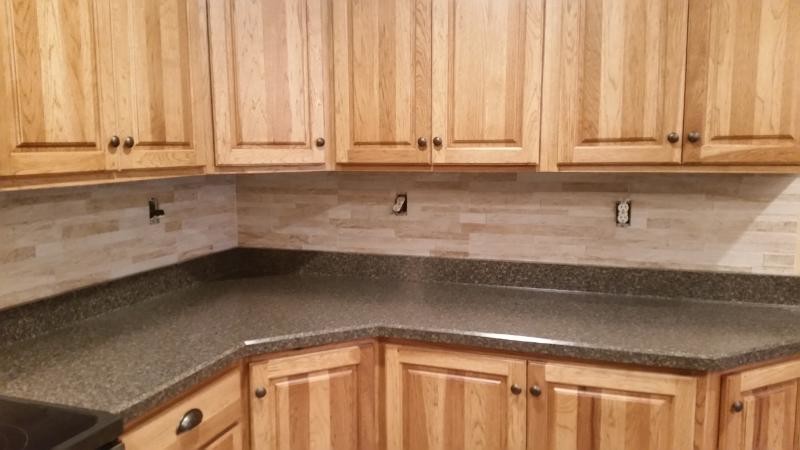 Kitchen - transitional kitchen idea in Chicago with raised-panel cabinets, medium tone wood cabinets, quartz countertops, beige backsplash, stone tile backsplash and stainless steel appliances