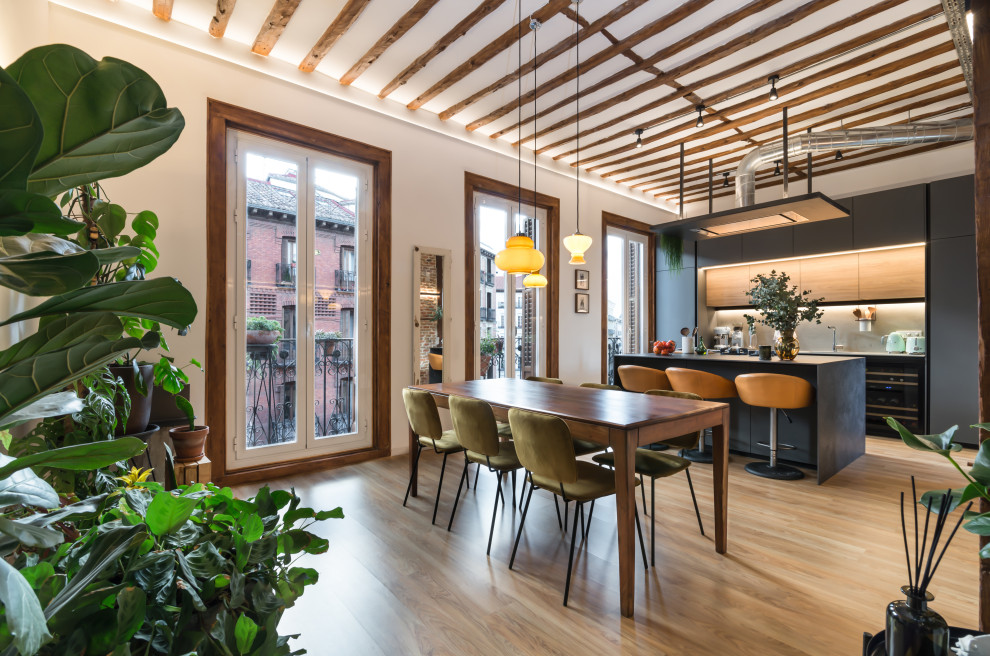 Idée de décoration pour une salle à manger ouverte sur le salon urbaine avec un mur blanc, un sol en bois brun, un sol marron et poutres apparentes.
