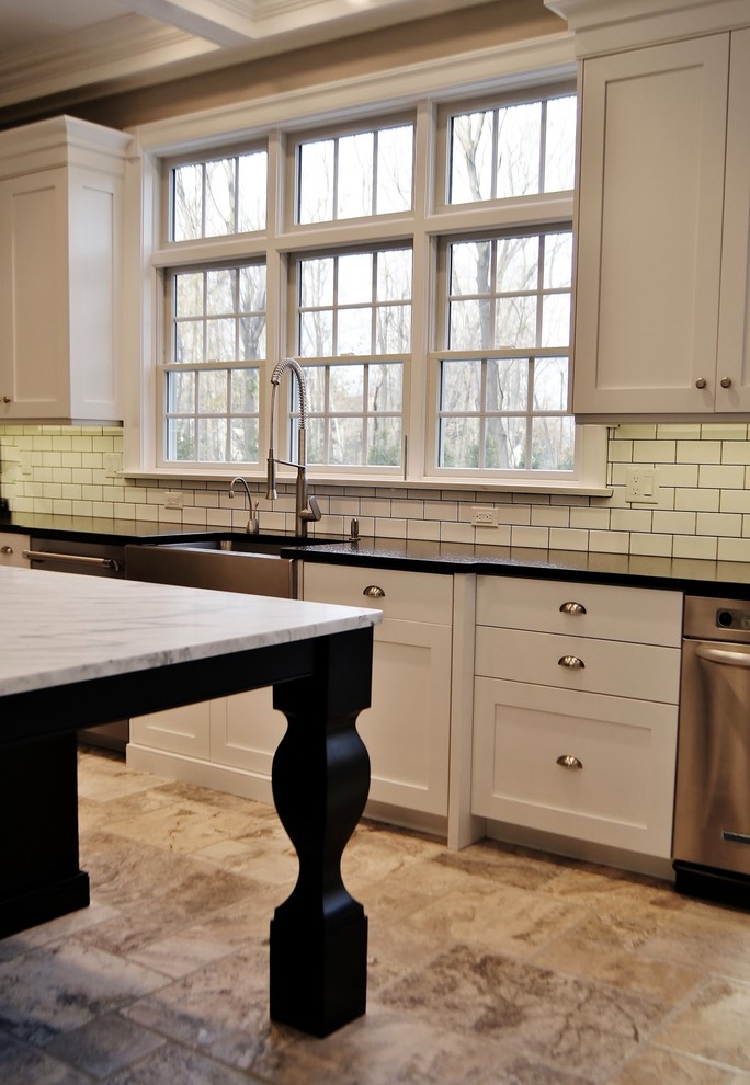 This is an example of a large transitional l-shaped eat-in kitchen in New York with a farmhouse sink, recessed-panel cabinets, white cabinets, granite benchtops, white splashback, ceramic splashback, stainless steel appliances, ceramic floors and with island.
