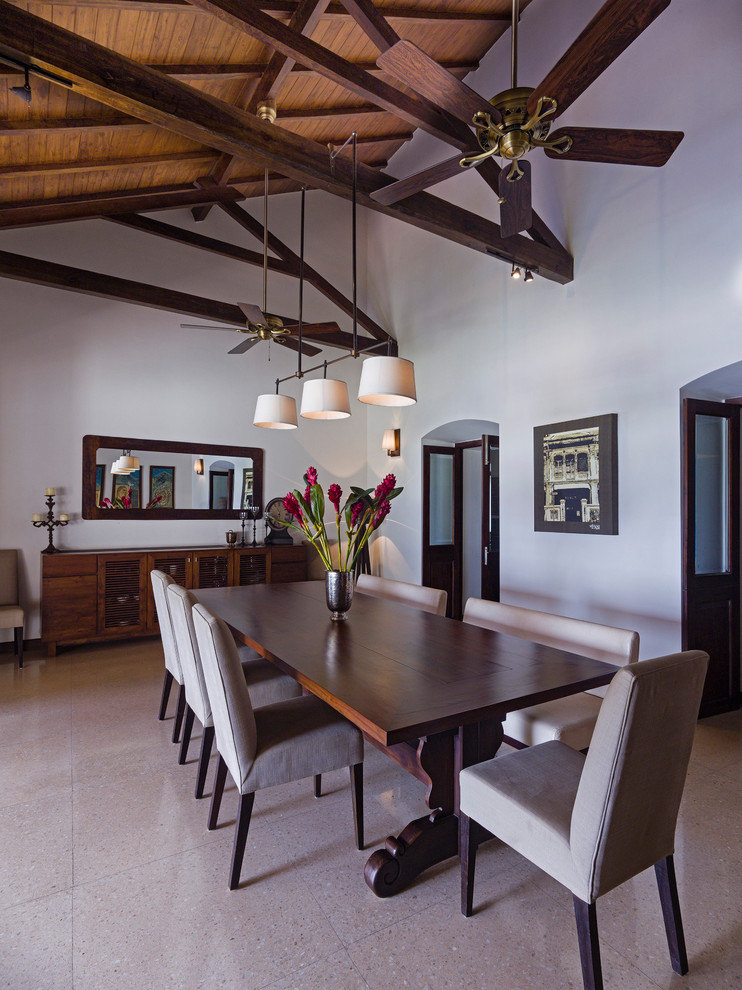 Photo of a large tropical separate dining room in Other with white walls, concrete floors and beige floor.