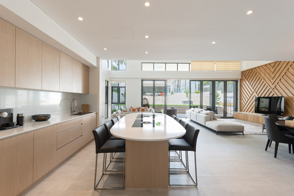 Photo of a contemporary single-wall kitchen in Sydney with flat-panel cabinets, light wood cabinets, with island, grey floor and white benchtop.
