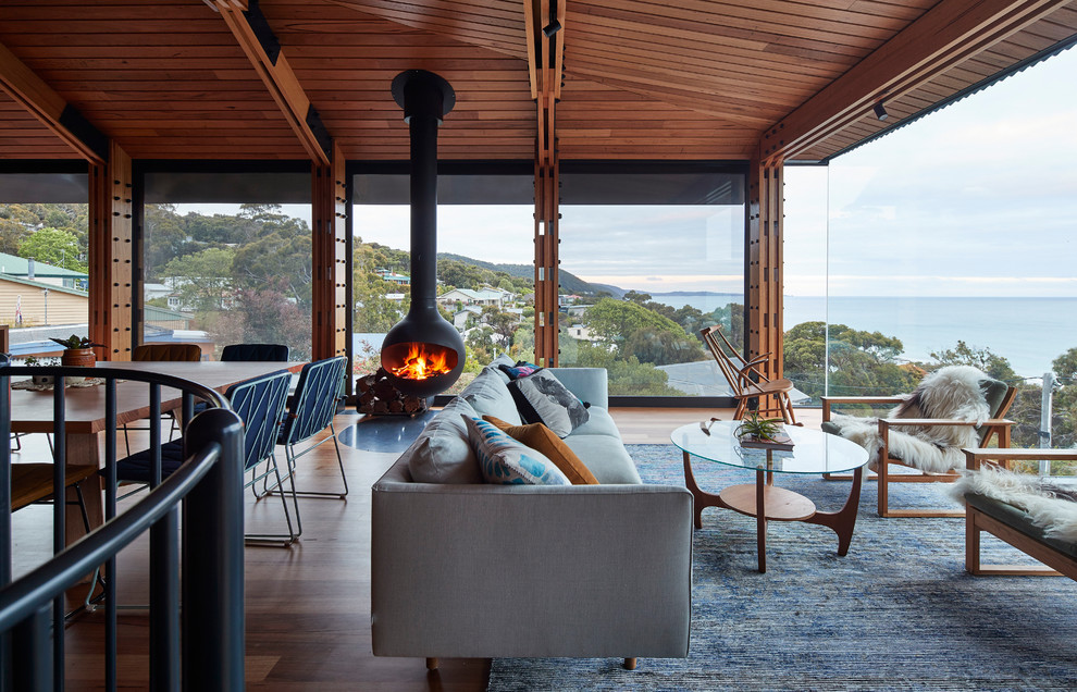 Contemporary open concept living room in Geelong with medium hardwood floors, a hanging fireplace, no tv and brown floor.