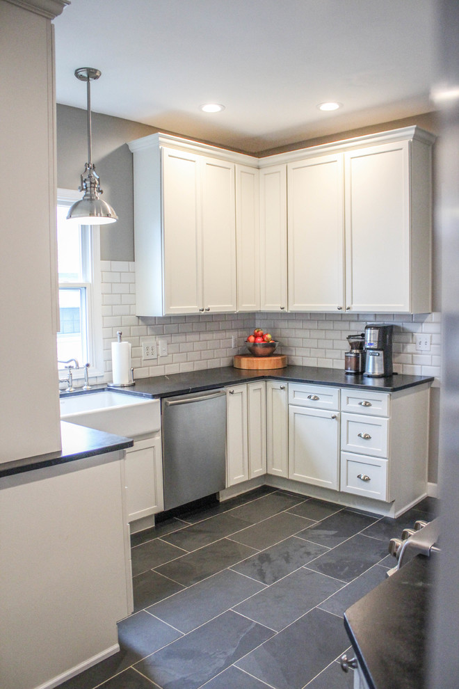 Country u-shaped gray floor eat-in kitchen photo in Cincinnati with a farmhouse sink, recessed-panel cabinets, white cabinets, soapstone countertops, white backsplash, subway tile backsplash and stainless steel appliances