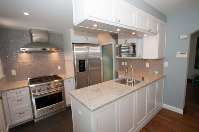 Large transitional u-shaped separate kitchen in DC Metro with a double-bowl sink, recessed-panel cabinets, medium wood cabinets, stainless steel appliances, ceramic floors, granite benchtops, metallic splashback, mosaic tile splashback, no island and grey floor.