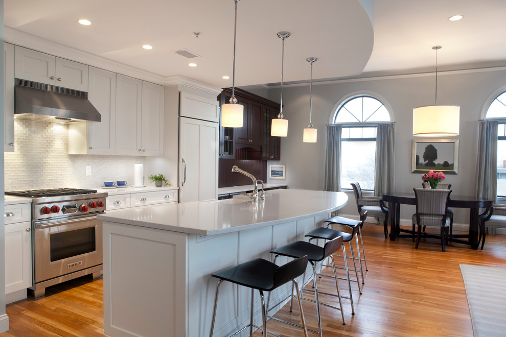 This is an example of a large transitional eat-in kitchen in Boston with an undermount sink, raised-panel cabinets, white cabinets, granite benchtops, beige splashback, travertine splashback, stainless steel appliances, porcelain floors and green benchtop.