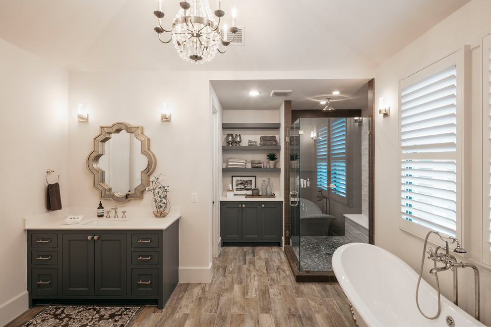 This is an example of a large transitional master bathroom in Houston with grey cabinets, white walls, an undermount sink, brown floor, white benchtops, a claw-foot tub, a corner shower, dark hardwood floors, a hinged shower door and shaker cabinets.