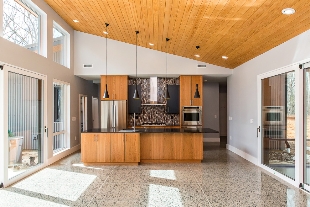 Mid-sized contemporary galley open plan kitchen in Raleigh with a single-bowl sink, flat-panel cabinets, medium wood cabinets, granite benchtops, brown splashback, glass tile splashback, stainless steel appliances, concrete floors, with island, grey floor, black benchtop and timber.