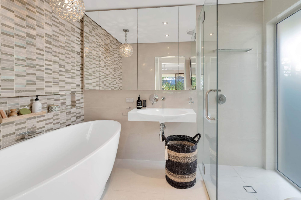 Photo of a mid-sized contemporary master bathroom in Gold Coast - Tweed with a drop-in tub, a corner shower, beige tile, gray tile, porcelain tile, porcelain floors, a wall-mount sink, beige floor, a hinged shower door, a niche and a single vanity.