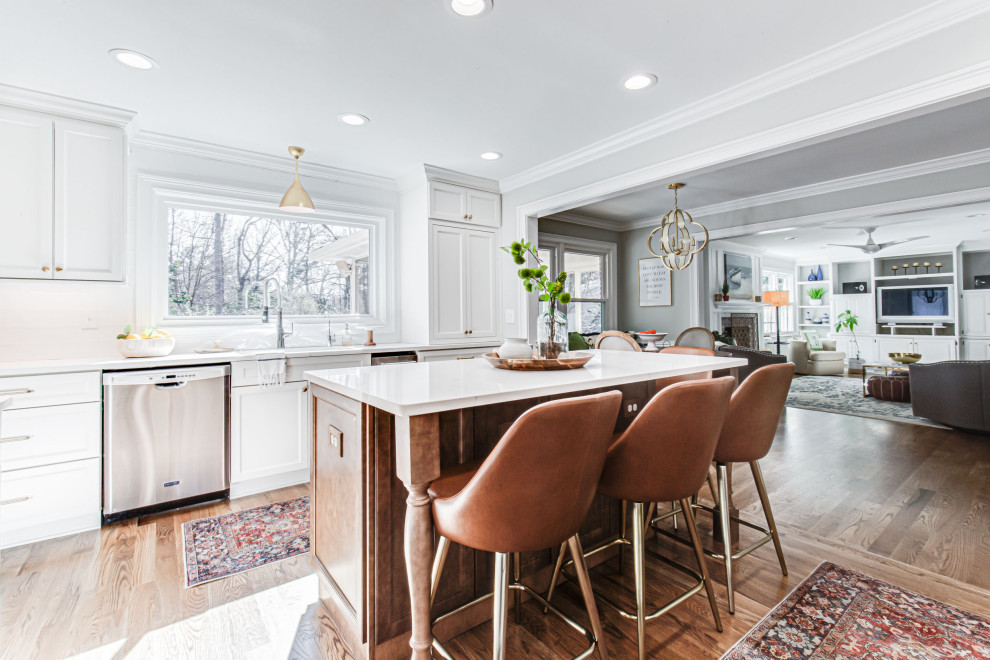 This is an example of a mid-sized transitional u-shaped open plan kitchen in Atlanta with an undermount sink, shaker cabinets, white cabinets, quartz benchtops, white splashback, subway tile splashback, stainless steel appliances, medium hardwood floors, with island and white benchtop.