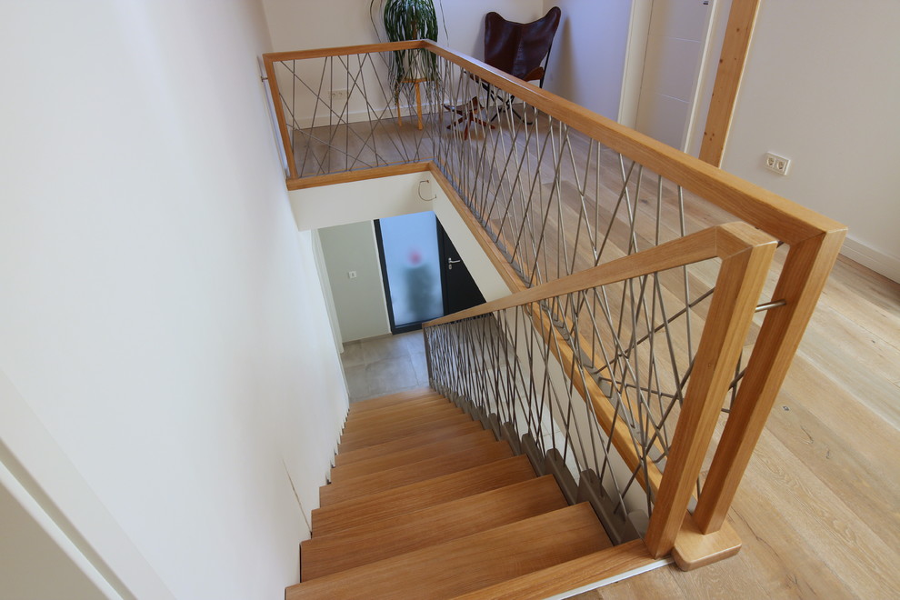 Idée de décoration pour un escalier droit de taille moyenne avec des marches en bois et un garde-corps en matériaux mixtes.