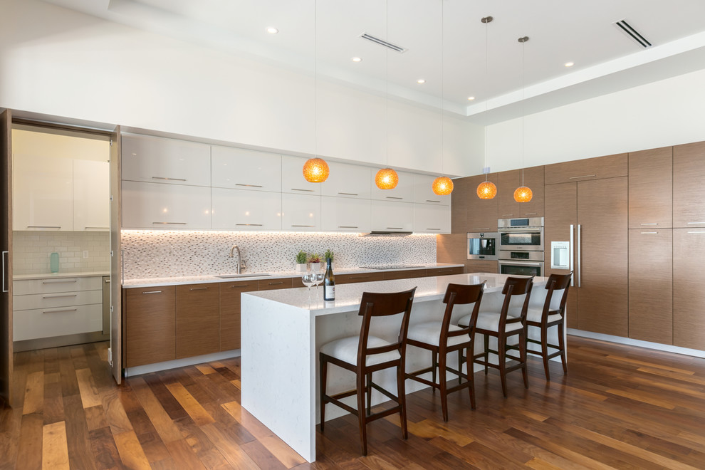 Design ideas for a large contemporary kitchen in Tampa with an undermount sink, flat-panel cabinets, quartz benchtops, multi-coloured splashback, panelled appliances, medium hardwood floors, with island and medium wood cabinets.