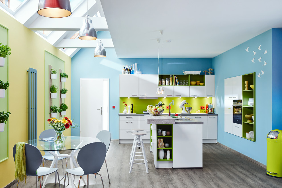 Inspiration for a large contemporary eat-in kitchen in Hamburg with flat-panel cabinets, white cabinets, green splashback, with island, medium hardwood floors and black appliances.