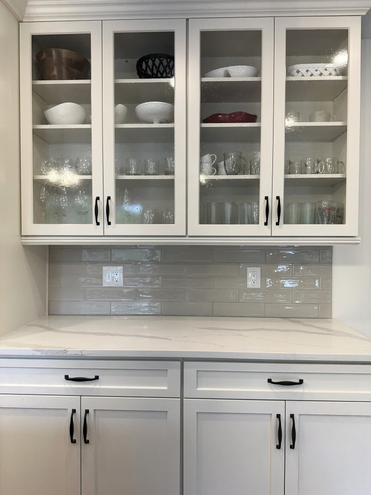 Mid-sized transitional u-shaped medium tone wood floor and brown floor eat-in kitchen photo with an undermount sink, flat-panel cabinets, white cabinets, quartz countertops, beige backsplash, ceramic backsplash, stainless steel appliances, an island and white countertops