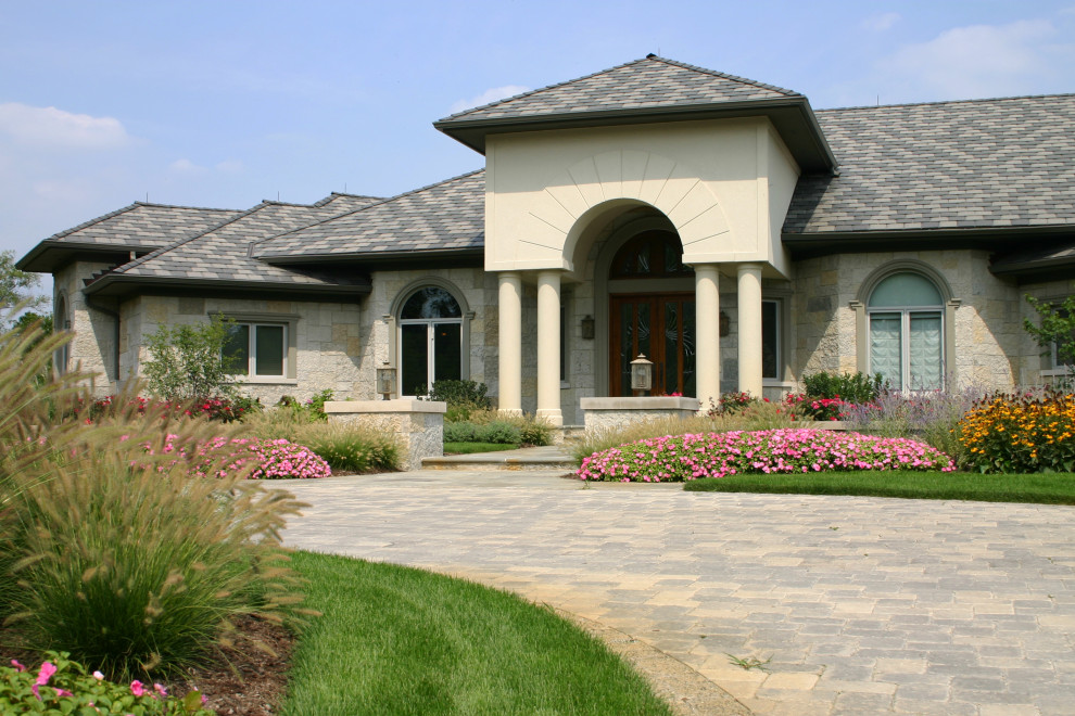 Пример оригинального дизайна: большой, двухэтажный, бежевый дом в современном стиле с облицовкой из камня и вальмовой крышей