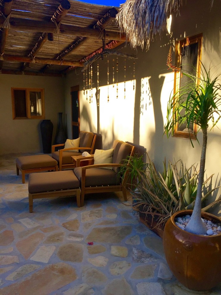 Foto de terraza tropical de tamaño medio en patio delantero con adoquines de hormigón y pérgola