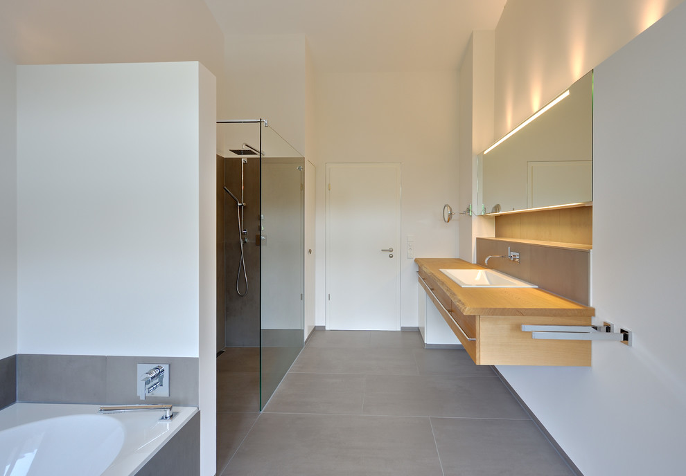 Large contemporary bathroom in Bremen with flat-panel cabinets, medium wood cabinets, a drop-in tub, an open shower, white walls, slate floors, a drop-in sink, wood benchtops and an open shower.