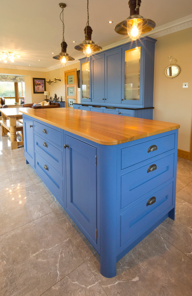 Photo of a large transitional l-shaped eat-in kitchen in Dublin with an undermount sink, shaker cabinets, blue cabinets, quartzite benchtops, black splashback, black appliances and with island.