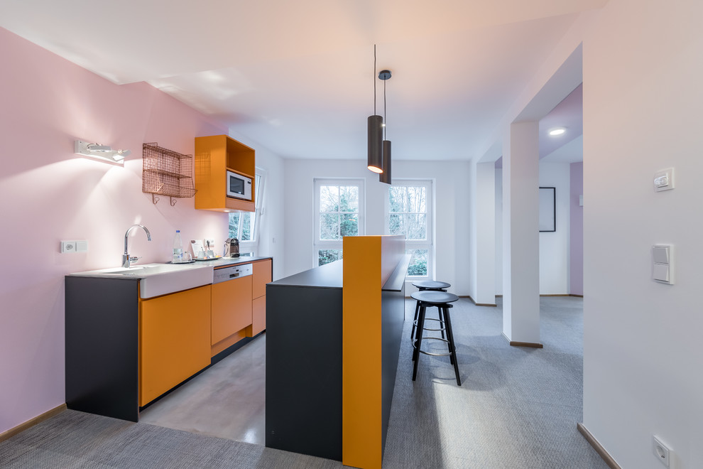 Photo of a small contemporary galley open plan kitchen in Frankfurt with an integrated sink, flat-panel cabinets, orange cabinets, laminate benchtops, pink splashback, glass sheet splashback, panelled appliances, concrete floors, with island and grey floor.