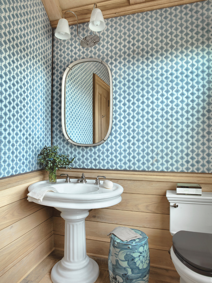This is an example of a country powder room in Austin with a pedestal sink, blue walls and a one-piece toilet.