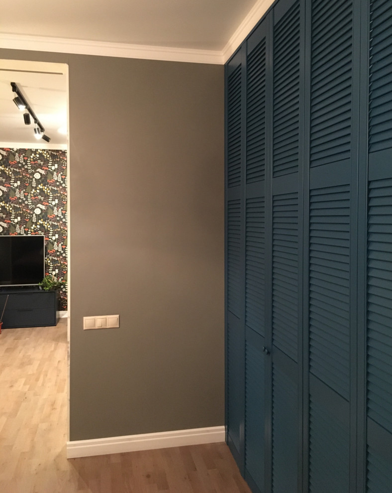 Photo of a large scandinavian walk-in wardrobe in Other with louvered cabinets, blue cabinets, laminate floors and beige floor.