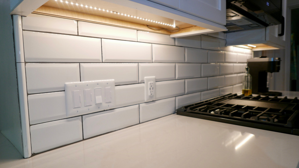 Mid-sized transitional galley porcelain tile and gray floor eat-in kitchen photo with an undermount sink, shaker cabinets, white cabinets, quartz countertops, white backsplash, subway tile backsplash, black appliances, no island and white countertops