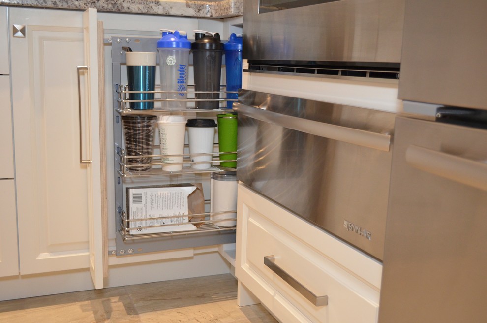 Inspiration for a mid-sized transitional l-shaped porcelain tile enclosed kitchen remodel in Toronto with an undermount sink, raised-panel cabinets, white cabinets, granite countertops, beige backsplash, stainless steel appliances and an island