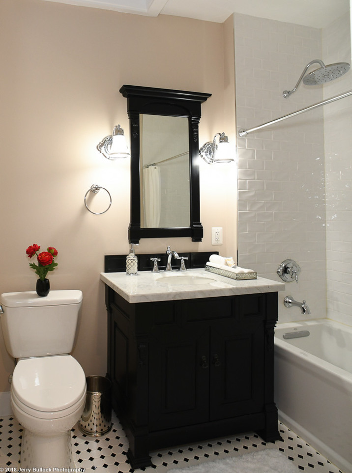 Inspiration for a mid-sized traditional 3/4 bathroom in DC Metro with furniture-like cabinets, black cabinets, a drop-in tub, a two-piece toilet, white tile, porcelain tile, beige walls, mosaic tile floors, an undermount sink, engineered quartz benchtops, white floor and white benchtops.