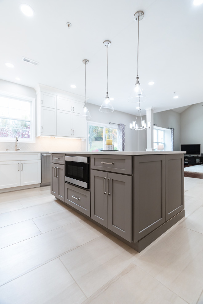 Photo of a large contemporary l-shaped open plan kitchen in Philadelphia with an undermount sink, shaker cabinets, white cabinets, quartzite benchtops, beige splashback, ceramic splashback, stainless steel appliances, porcelain floors, with island, beige floor and white benchtop.
