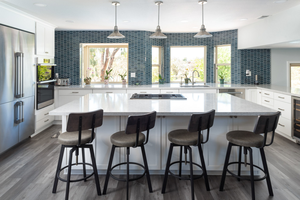 Design ideas for a large transitional u-shaped eat-in kitchen in San Diego with a single-bowl sink, recessed-panel cabinets, white cabinets, quartz benchtops, blue splashback, porcelain splashback, stainless steel appliances, vinyl floors, with island, grey floor and grey benchtop.