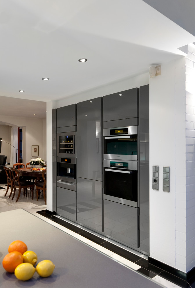 Large contemporary u-shaped open plan kitchen in Other with an undermount sink, flat-panel cabinets, grey cabinets, white splashback, glass sheet splashback, stainless steel appliances, marble floors, a peninsula, grey benchtop and quartz benchtops.