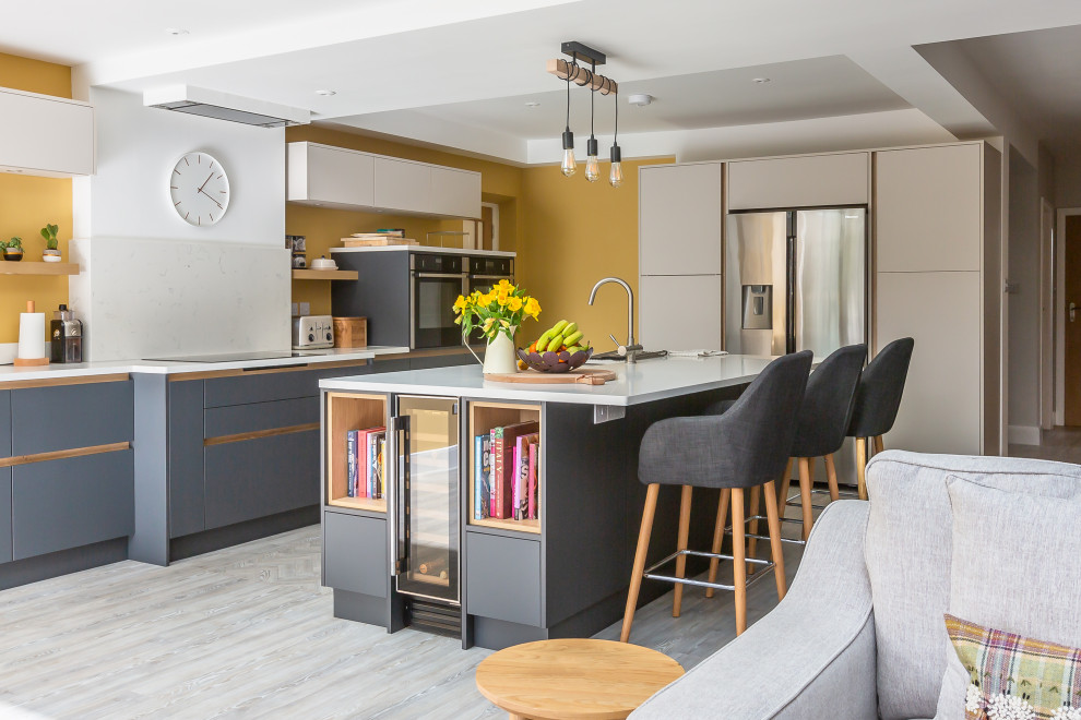 Photo of a scandinavian open plan kitchen in London with flat-panel cabinets, grey cabinets, yellow splashback, light hardwood floors, with island and white benchtop.