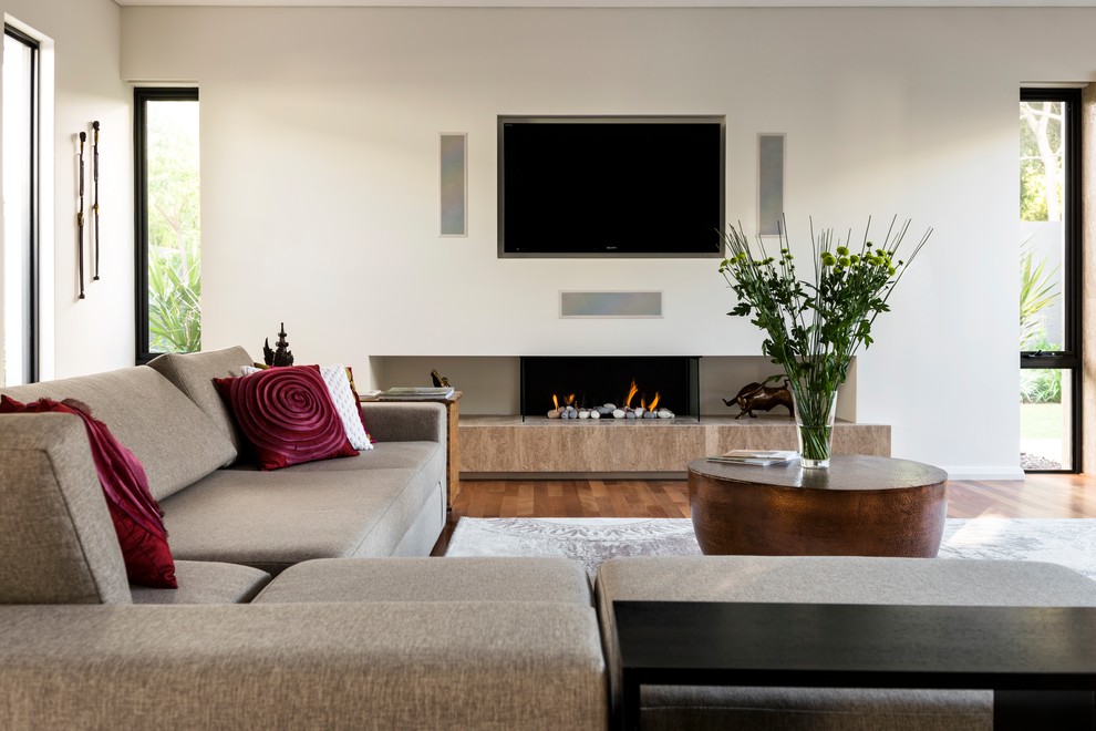 Large contemporary open concept living room in Perth with white walls, medium hardwood floors, a standard fireplace, a plaster fireplace surround, a built-in media wall and brown floor.