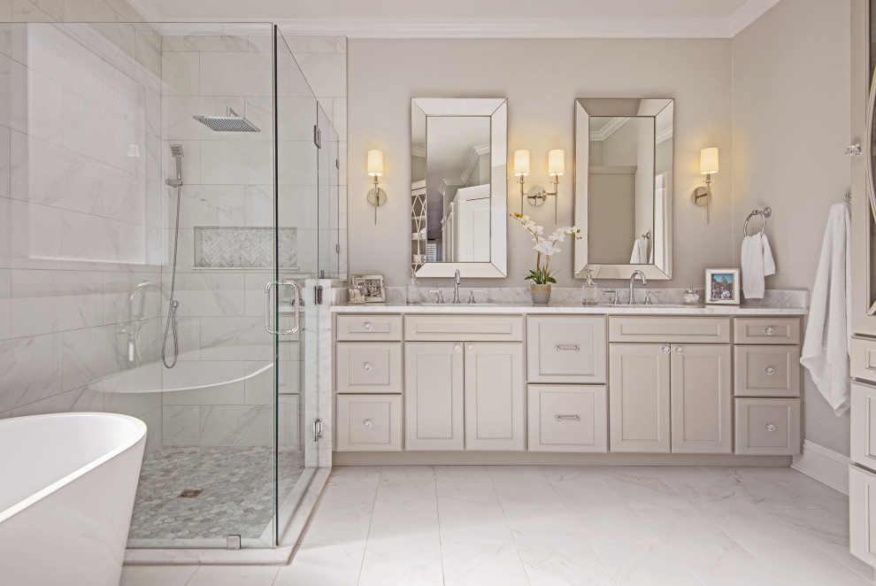This is an example of a large traditional master bathroom in Tampa with flat-panel cabinets, beige cabinets, a hot tub, a corner shower, a one-piece toilet, gray tile, marble, beige walls, marble floors, an undermount sink, engineered quartz benchtops, white floor, a sliding shower screen, white benchtops, a niche, a double vanity and a built-in vanity.
