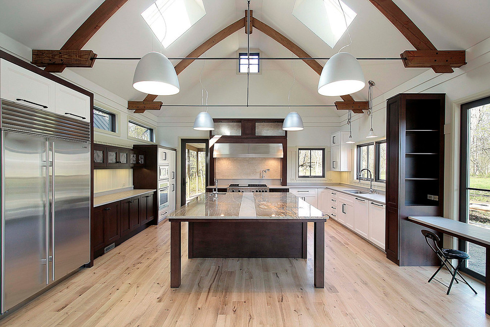 Inspiration for a transitional light wood floor and beige floor kitchen remodel in Orlando with an undermount sink, shaker cabinets, white cabinets, soapstone countertops, white backsplash, subway tile backsplash, stainless steel appliances and an island